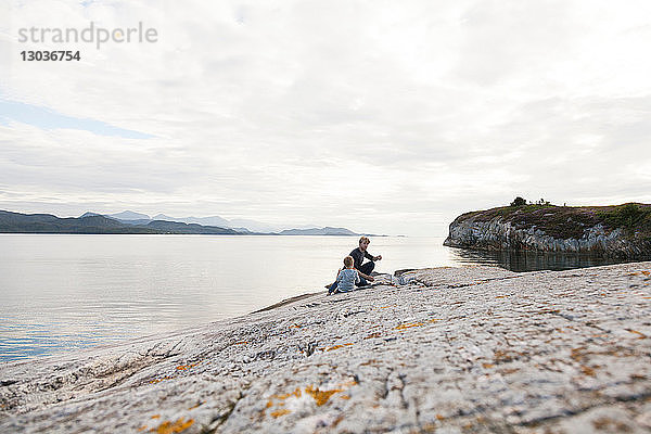 Junge und Vater essen Essen auf einem Einlauffelsen,  Aure,  More og Romsdal,  Norwegen