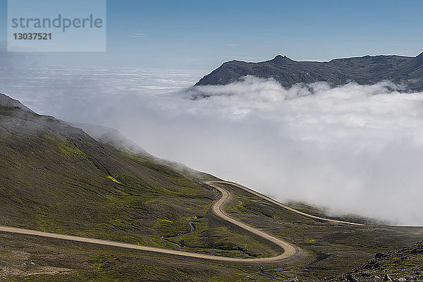 Landschaft mit einer Straße am Hang und Nebel in Borgafjordur Eystri,  Island