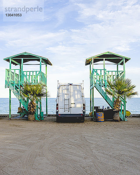 Von Rettungsschwimmerhütten am Strand geparktes Wohnmobil gegen den Himmel