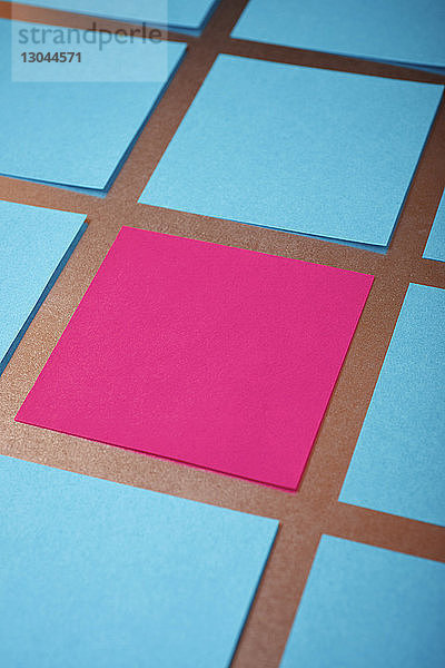 Hochwinkelansicht von blauen und rosa Papieren,  die auf einem Tisch angeordnet sind