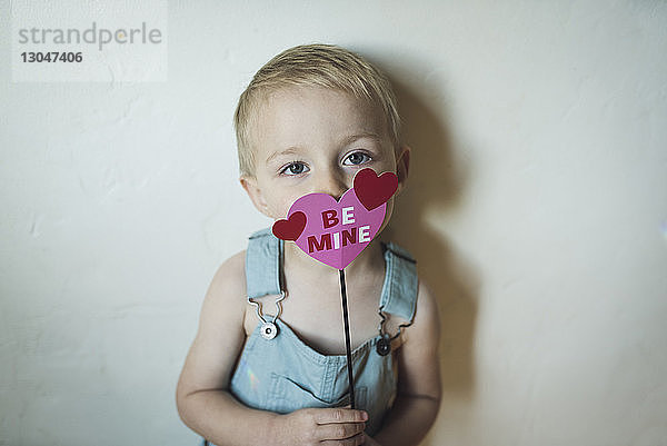 Porträt eines süßen Jungen in Herzform mit Be Mine Text an der Wand