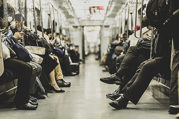 Fahrgäste,  die während der Fahrt in der U-Bahn auf Sitzen sitzen