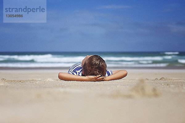 Oberflächenniveau eines Jungen,  der sich an einem sonnigen Tag am Strand entspannt