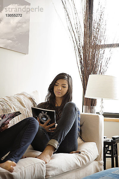 Freunde lesen Buch,  während sie zu Hause auf dem Sofa liegen