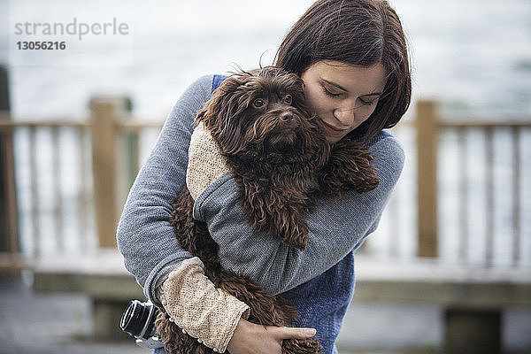 Frau umarmt Hund,  während sie am Hudson River steht