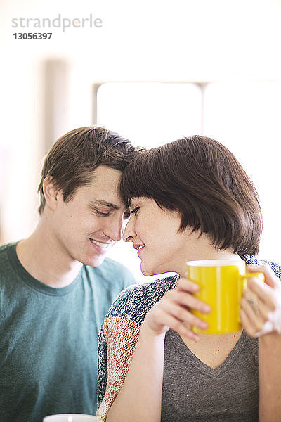 Frau trinkt Kaffee,  während sie mit ihrem Freund zu Hause sitzt