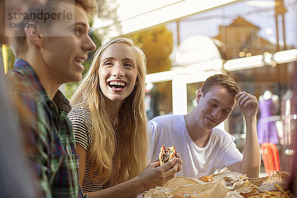 Glückliche Freunde essen im Straßencafé