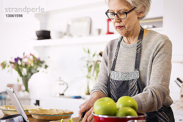 Äpfel schneidende ältere Frau bei Tisch in der Küche