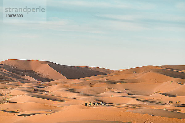 Menschen mit Kamelen in der Wüste Merzouga gegen den Himmel