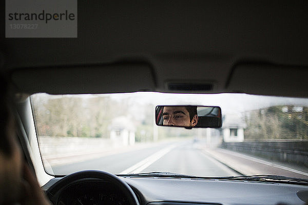 Spiegelung des Menschen im Autorückspiegel auf der Straße