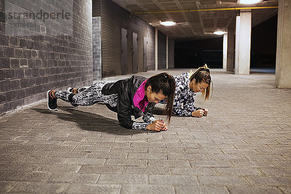 Entschlossene Sportlerinnen bei Plankenübungen im Tunnel