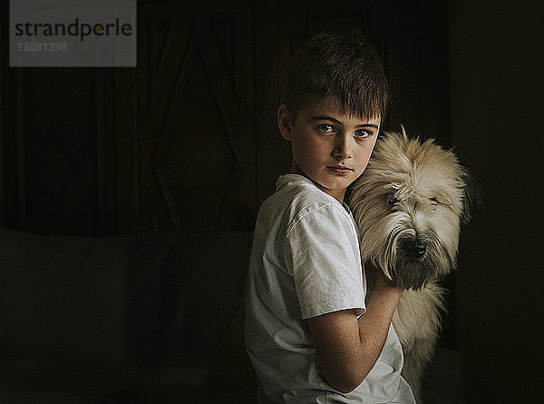 Porträt eines Jungen mit Hund,  der zu Hause in der Dunkelkammer steht