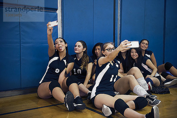 Spielerinnen,  die auf dem Boden sitzen und sich auf dem Volleyballfeld klicken
