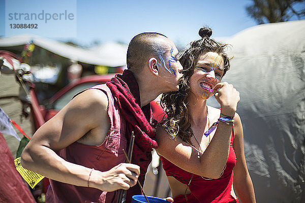 Fröhlicher Mann und Frau mit Gesichtsbemalung genießen während der traditionellen Veranstaltung
