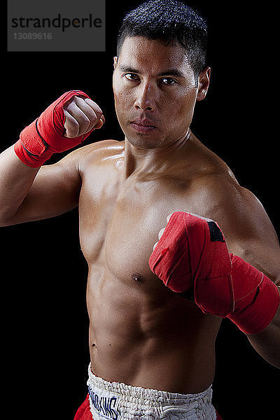 Porträt eines selbstbewussten Boxers ohne Hemd vor schwarzem Hintergrund