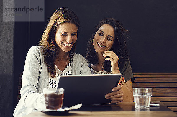 Fröhliche reife Freundinnen benutzen Tablet-Computer im Café