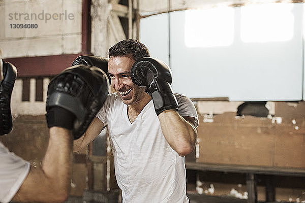 Glücklicher männlicher Boxer trainiert mit einem älteren Mann im Fitnessstudio