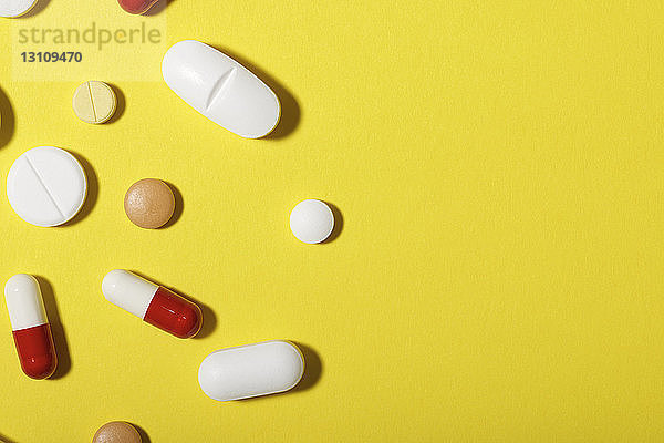 Hochwinkelansicht verschiedener Medikamente über gelbem Hintergrund