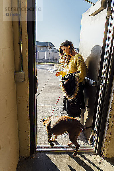 Seitenansicht einer am Eingang stehenden Frau mit Hund