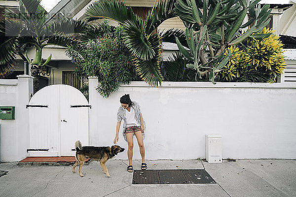 Frau mit Hund beim Spaziergang auf dem Bürgersteig
