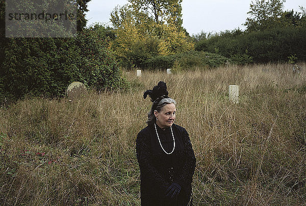 Traurige Frau schaut weg,  während sie auf dem Friedhof steht
