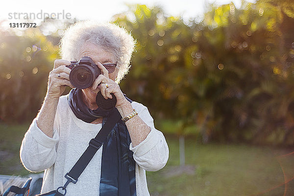 Ältere Frau fotografiert durch Kamera im Park