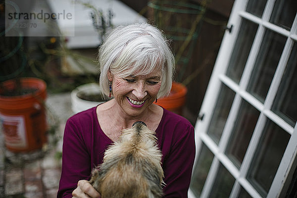 Schrägansicht einer fröhlichen älteren Frau mit Hund im Hof