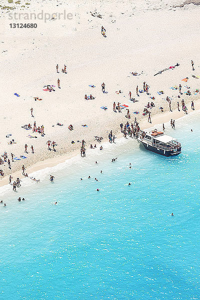 Hochwinkelaufnahme von Menschen am Strand des Schiffswracks bei Sonnenschein