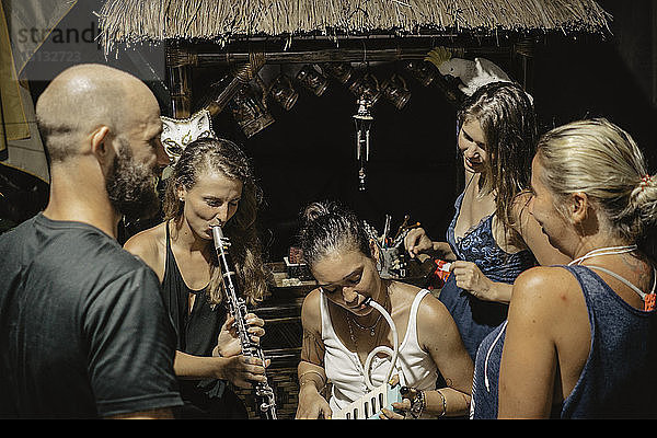 Freunde schauen auf Frauen,  die Blasinstrumente in einem Touristenort spielen