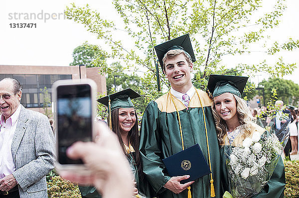 Ausschnitt einer Person,  die Studenten bei der Abschlussfeier fotografiert