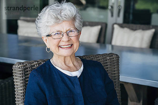 Porträt einer lächelnden älteren Frau,  die auf der Veranda sitzt