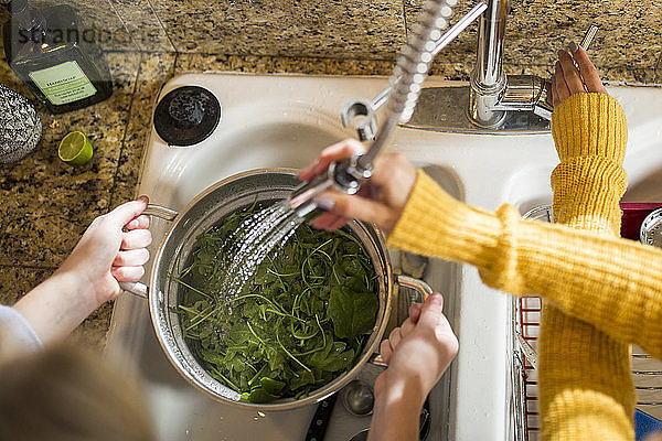 Ausgeschnittenes Bild von Händen,  die Gemüse an der Küchenspüle waschen