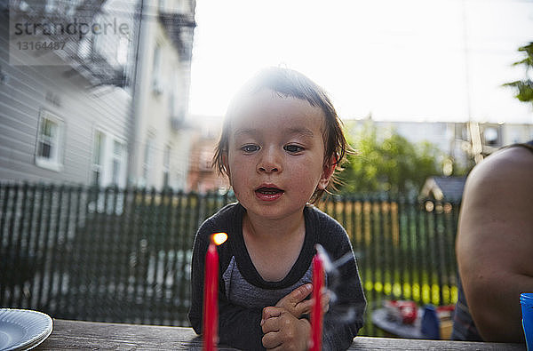 Junge betrachtet brennende Kerze auf dem Esstisch