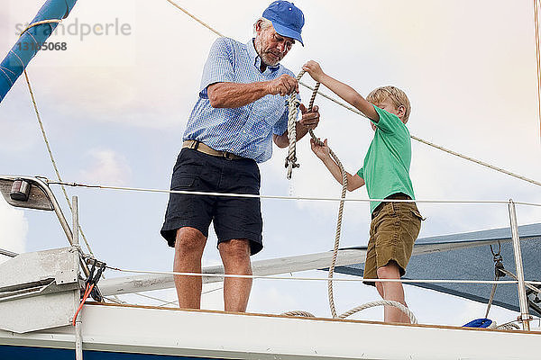 Junge und Grossvater knüpfen Taue auf einem Segelboot