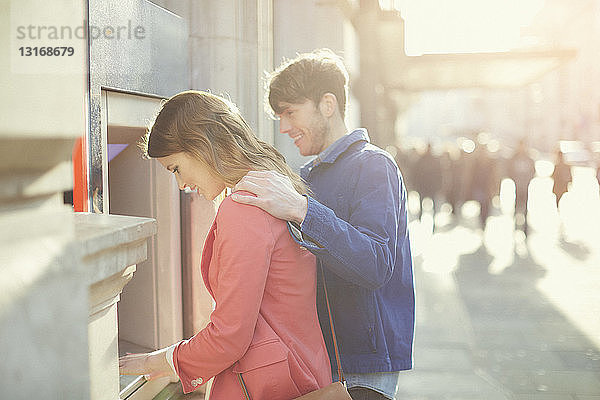 Ehepaar,  das Geld am Geldautomaten auf der Straße abhebt,  London,  UK