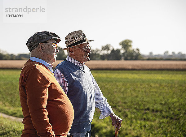 Zwei alte Freunde stehen auf den Feldern und reden über alte Zeiten