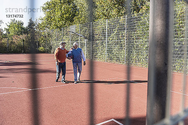 Zwei fitte Senioren amüsieren sich auf einem Basketballfeld