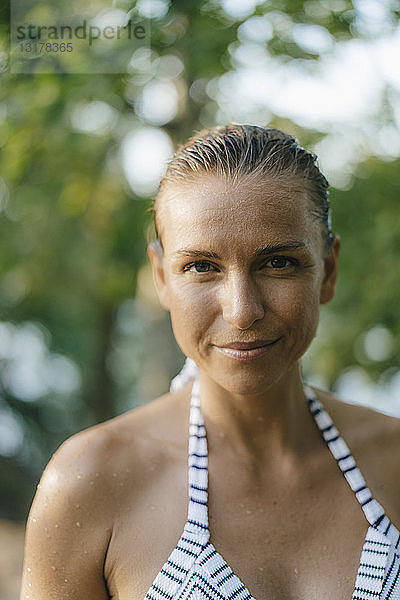 Porträt einer lächelnden Frau mit nassem Haar im Bikini