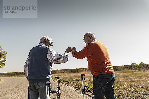 Zwei alte Freunde mit Gehhilfen auf Rädern,  Begrüßung auf der Straße
