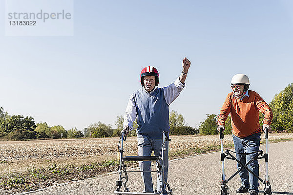 Zwei alte Freunde tragen Schutzhelme und nehmen an einem Laufrad-Rennen teil