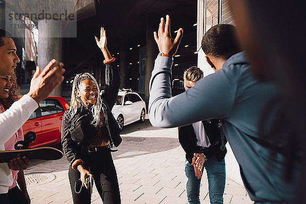 Glückliche multiethnische Freunde tanzen an sonnigen Tagen auf der Straße der Stadt