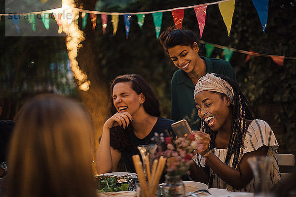 Fröhliche multi-ethnische Freunde genießen bei Tisch während der Dinnerparty im Hinterhof