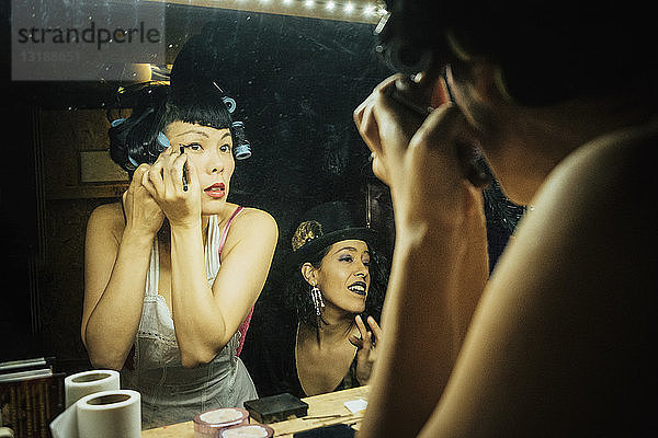 Burlesque-Darstellerinnen machen sich bereit und schminken sich vor dem Spiegel in der Garderobe