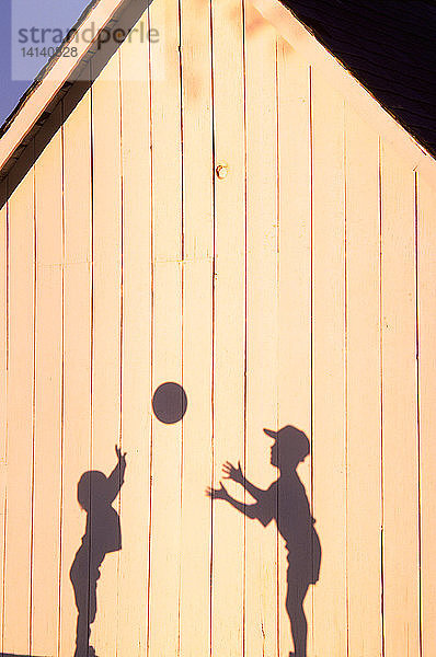 Shadow of kids playing catch with ball
