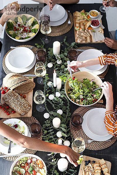 Freunde sitzen am gedeckten Tisch,  genießen ihre Dinnerparty,  Blick von oben