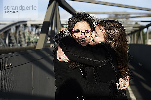 Glückliche Freunde,  die sich auf einer Brücke umarmen