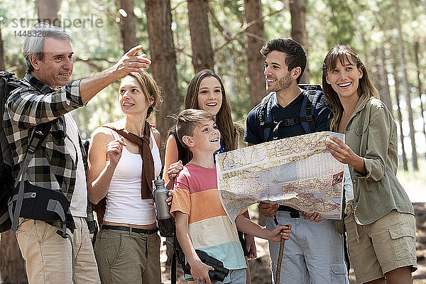 Familie,  die im Wald stehend eine Karte liest