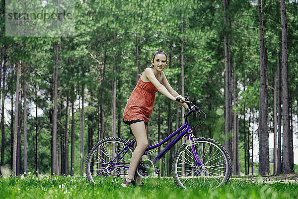Teenager-Mädchen sitzt auf einem Fahrrad im Wald