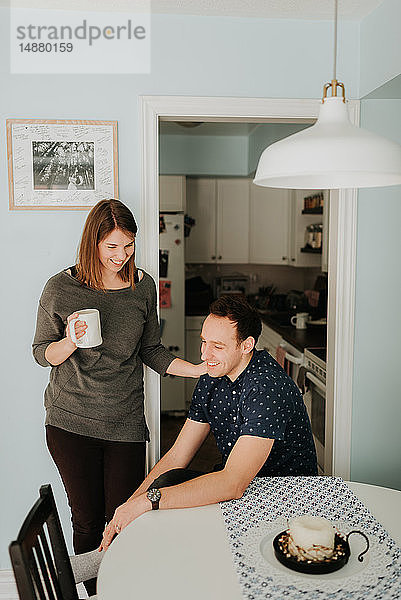 Mittleres erwachsenes Paar macht Kaffeepause am Küchentisch