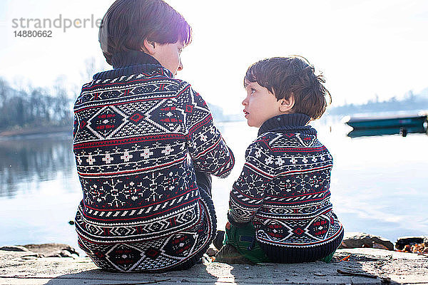 Junge und kleiner Bruder im passenden Pullover im Gespräch am Pier,  Comer See,  Lecco,  Lombardei,  Italien